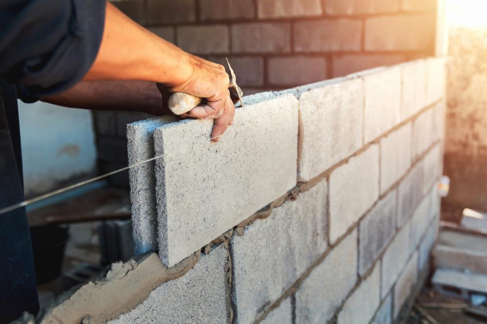 Ouvrier construisant un mur en briques et ciment